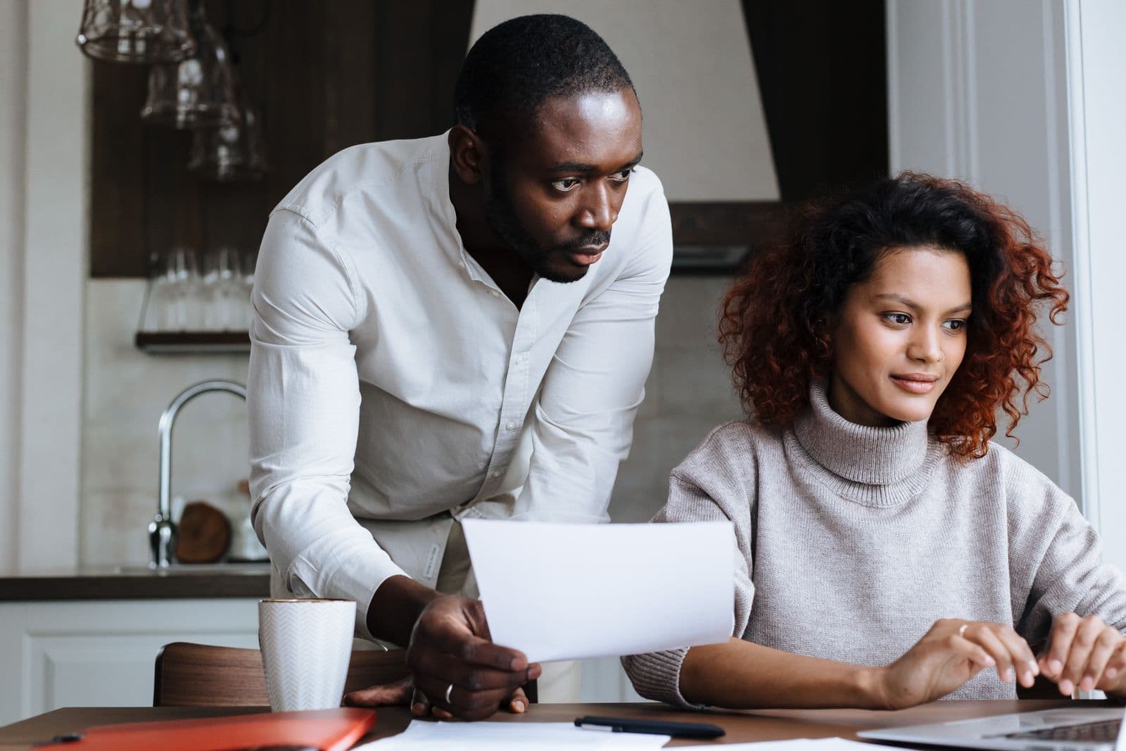 A couple going through household paperwork together at the kitchen table